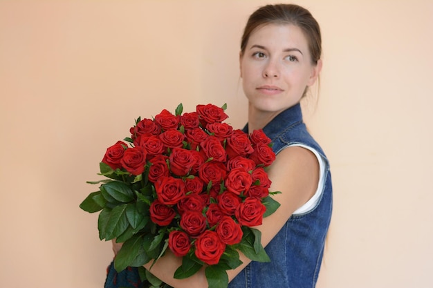 Mädchen mit einem Strauß roter Rosen im Hintergrund
