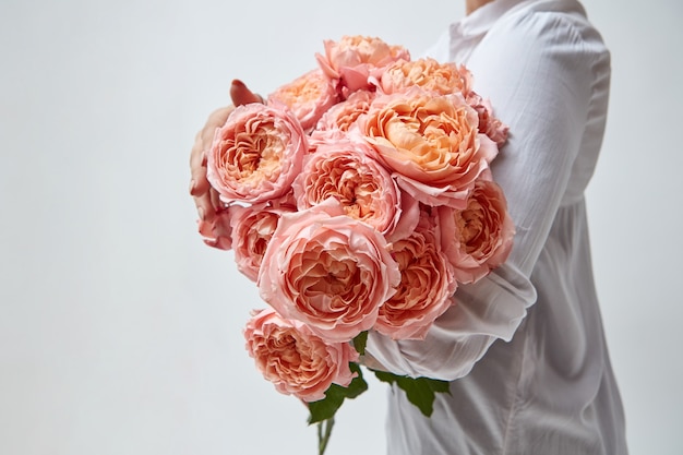 Mädchen mit einem Strauß schöner rosa Medienrosen auf grauem Hintergrund. Muttertag, Valentinstag