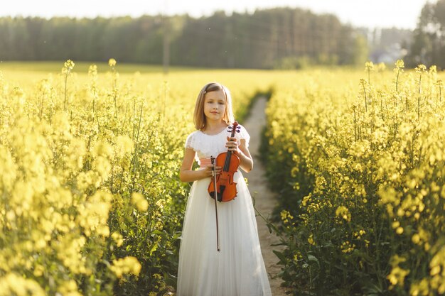 Mädchen mit einer Geige auf einem Feld im Sommer