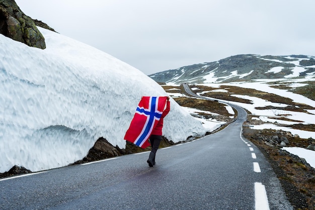 Mädchen mit einer norwegischen Flagge auf einer Bergstraße in Norwegen