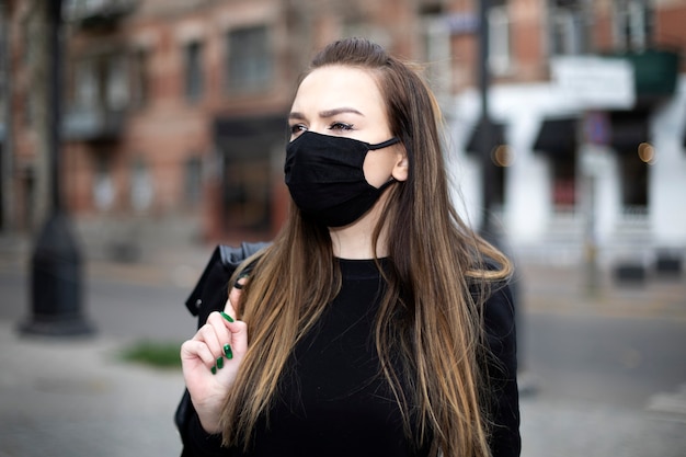 Mädchen mit einer schwarzen Maske auf ihrem Gesicht geht um die Stadt