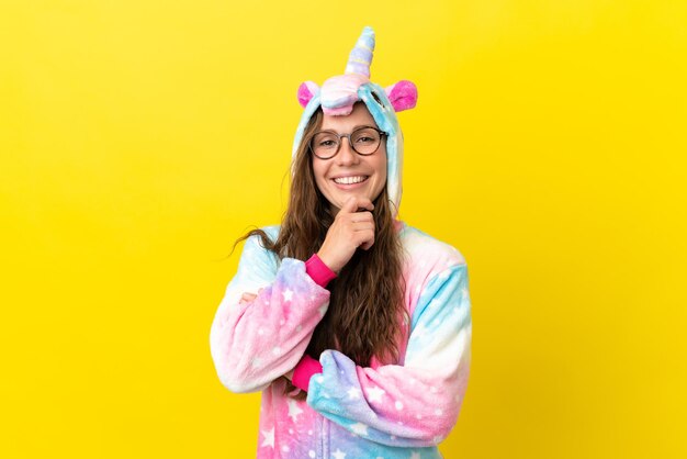 Mädchen mit Einhorn-Pyjama über isoliertem Hintergrund mit Brille und lächelnd