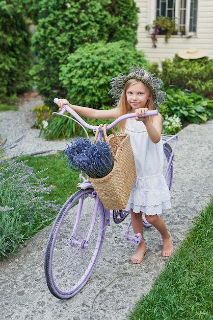 Mädchen mit Fahrrad und Lavendel im Sommer auf dem Hof