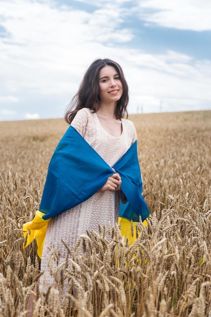 Mädchen mit Flagge der Ukraine und Spaziergänge über ein Feld von reifem Weizen