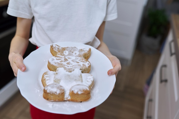 Mädchen mit frisch gebackenem Muffin, bestreut mit Puderzucker. Cupcake in Katzenform