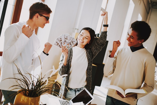 Mädchen mit Geld im Büro freut sich.