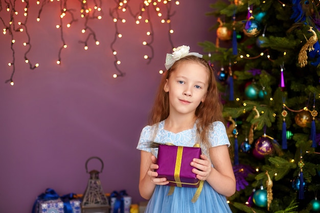 Mädchen mit Geschenkbox nahe Weihnachtsbaum