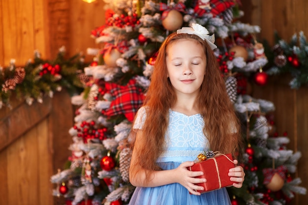 Mädchen mit Geschenkbox nahe Weihnachtsbaum