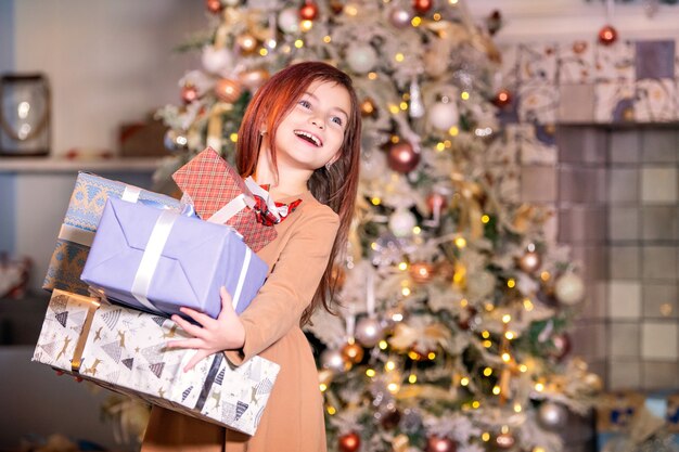 Mädchen mit Geschenkboxen gegen den Weihnachtsbaum