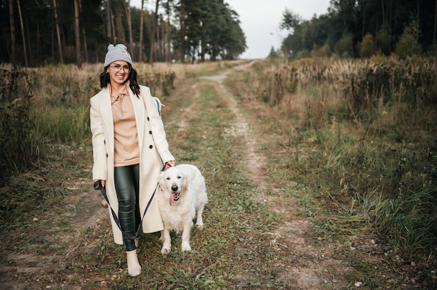 Mädchen mit goldenem Retrieverhund, der auf Waldweg geht