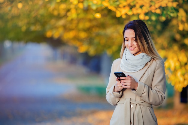 Mädchen mit Handy auf Herbstsaisonstraße