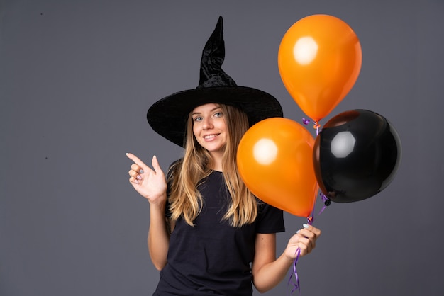 Mädchen mit Hexenkostüm für Halloween-Party und Zeigen auf die Seite