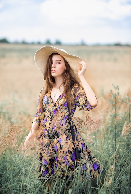 Mädchen mit Hut, der auf einem Feld im Sommer steht