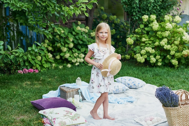 Mädchen mit Hut im Garten bei einem Picknick