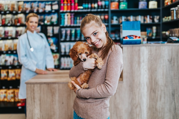 Foto mädchen mit ihrem pudelwelpen beim tierarzt