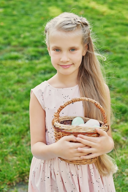 Mädchen mit Kaninchen und Eiern für Ostern im Park auf grünem Gras