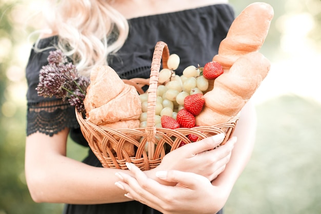 Mädchen mit Korb mit frischem Brot, Erdbeertrauben, Croissant im Park Bereiten Sie sich auf ein Picknick vor