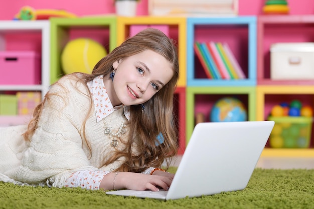 Mädchen mit Laptop auf dem Teppich liegend