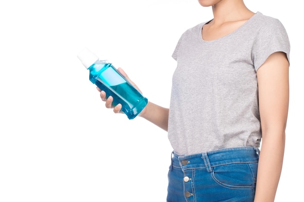 Mädchen mit leerem grauen T-Shirt, Jeans hält eine Mundwasserflasche isoliert auf weißem Hintergrund.