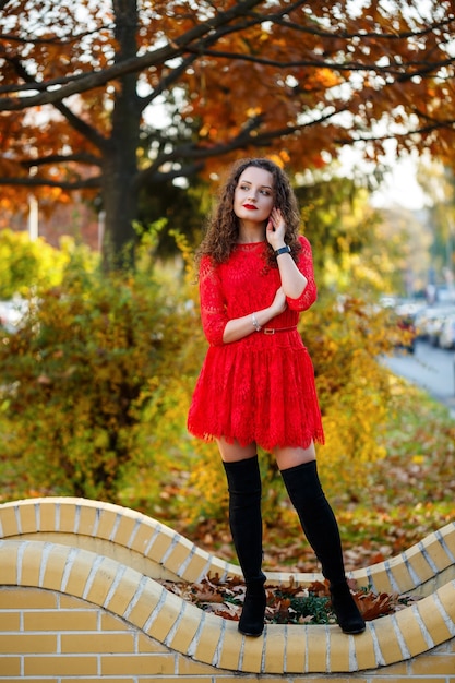 Mädchen mit Locken in einem roten Kleid auf einer herbstlichen Stadtgasse