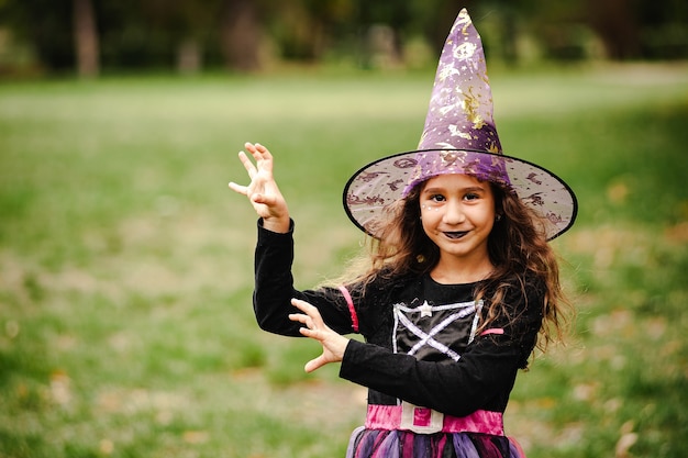 Mädchen mit lockigem Haar in einem Hexenkostüm für Halloween