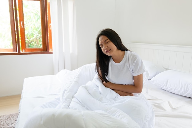 Mädchen mit Magenschmerzen auf dem Bett im Schlafzimmer zu Hause