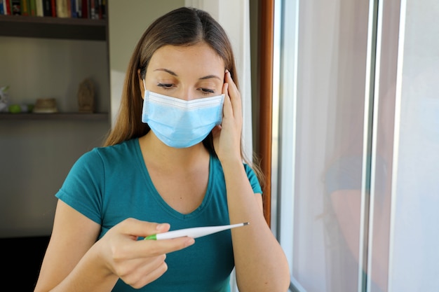 Mädchen mit Maske auf Gesicht überprüfen Fieber ein Symptom der Coronavirus-Krankheit 2019.