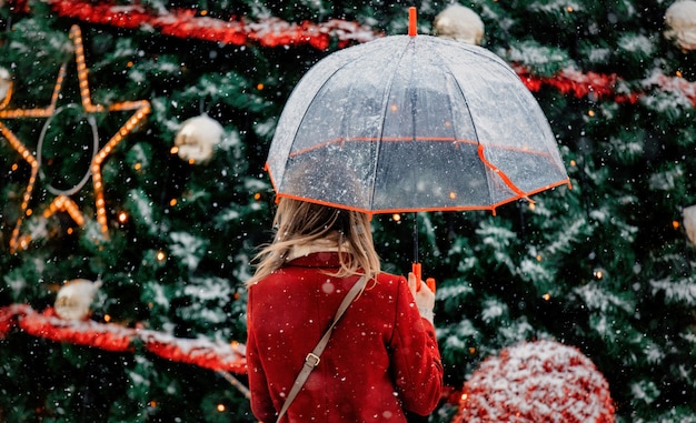 Mädchen mit Regenschirm nahe Weihnachtsbaum