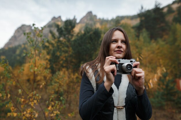 Mädchen mit Retro-Kamera in den Herbstbergen