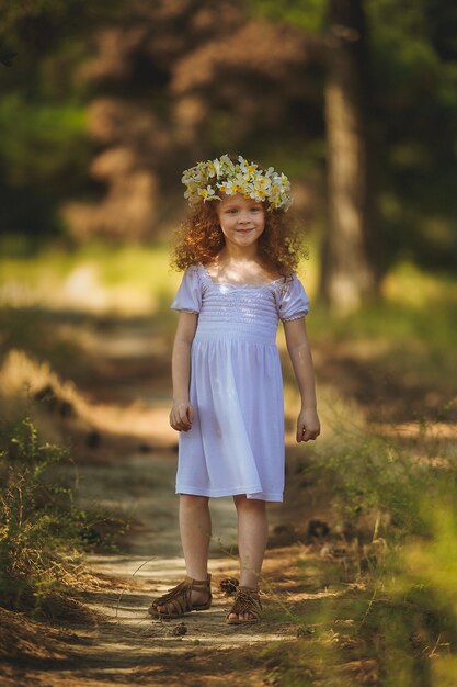 Mädchen mit roten Haaren, das mit Blumen in den Wald geht