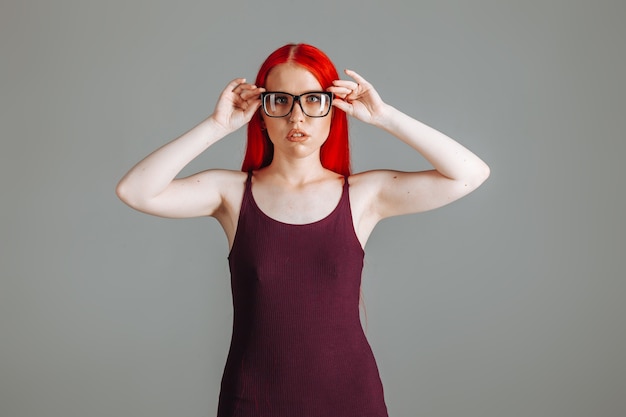 Mädchen mit roten langen Haaren berührt eine Brille