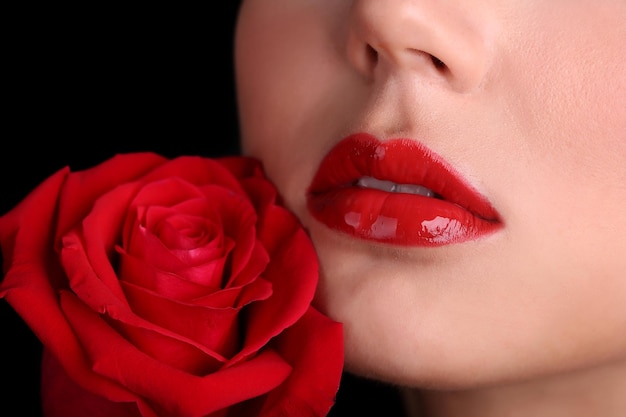 Mädchen mit roten Lippen und Rose auf dunklem Hintergrund