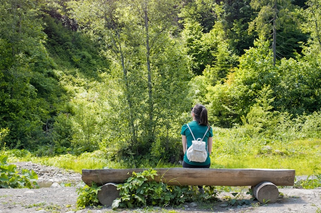 Mädchen mit Rucksack den Wald bewundernd. Rückansicht. Sommertag sonnig