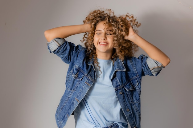 Mädchen mit schöner klarer Haut in einer Jeansjacke auf Haarprodukten mit grauem Hintergrund