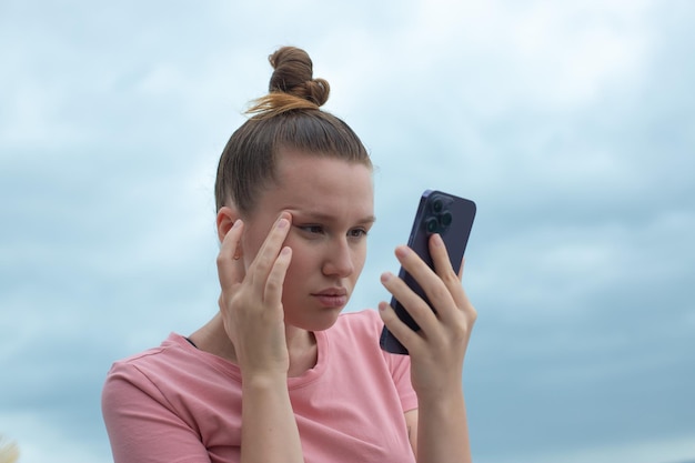 Mädchen mit Sehproblemen versucht, Text am Telefon zu lesen. Schlechtes Sehkonzept. Frau schaut auf das