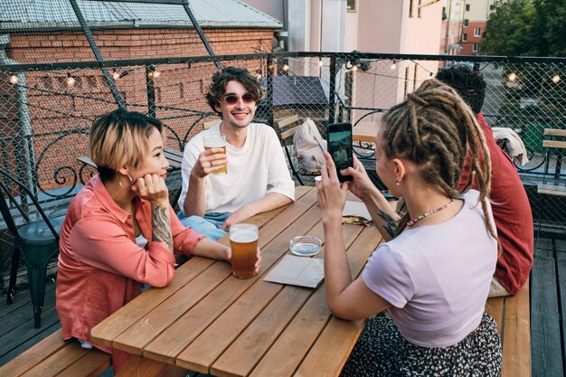 Mädchen mit Smartphone fotografiert ihre Freunde mit Getränken