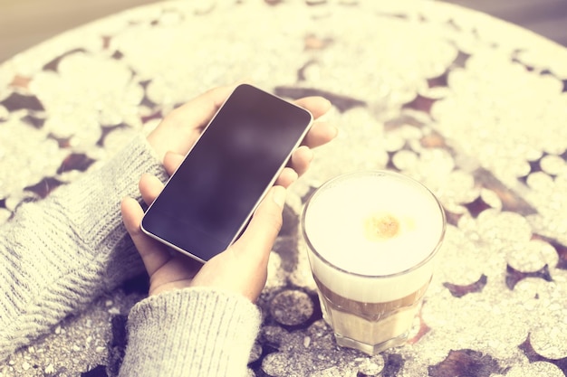 Mädchen mit Smartphone und Tasse Kaffee