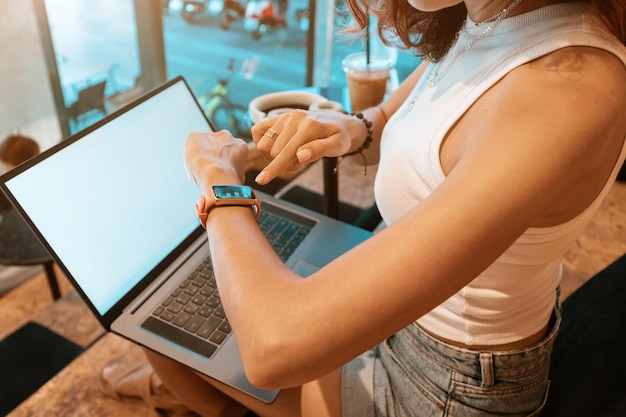 Mädchen mit Smartwatch arbeitet am Laptop im Café Zeitmanagement-Konzept