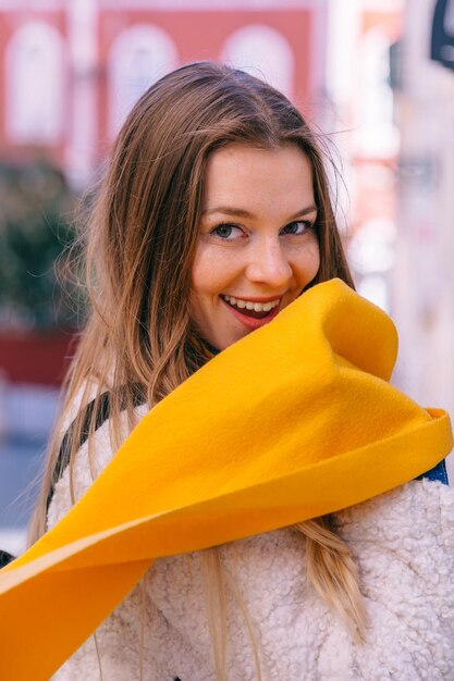 Foto mädchen mit sommersprossen und einem gelben schal lächelt geheimnisvoll auf th