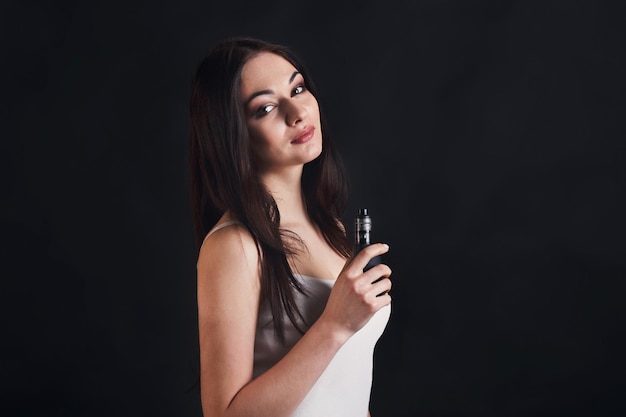 Mädchen mit Vape an der schwarzen Studiohintergrundnahaufnahme. Junge Frau raucht E-Zigarette, um mit dem Tabak aufzuhören. Nikotinfreies Rauchen und Dampfkonzept, Kopierraum