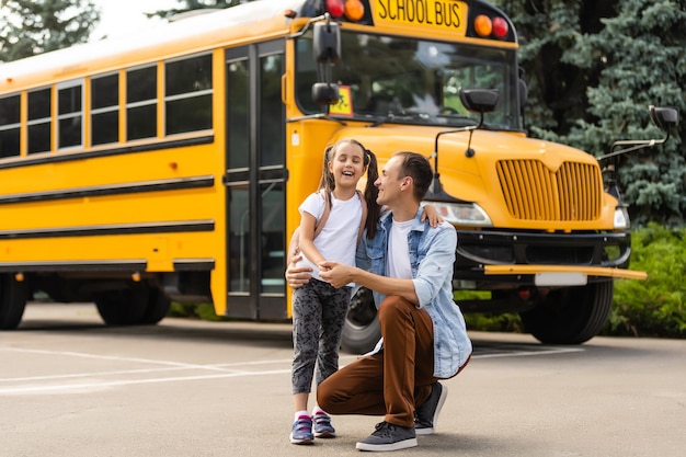 Mädchen mit Vater, der in der Nähe des Schulbusses zurück zur Schule geht