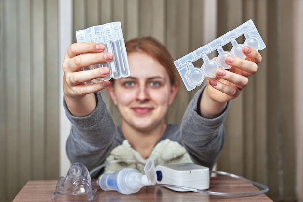 Mädchen mit Vernebler zur Behandlung von Atemwegserkrankungen bereitet Medikamente zur Inhalation vor.