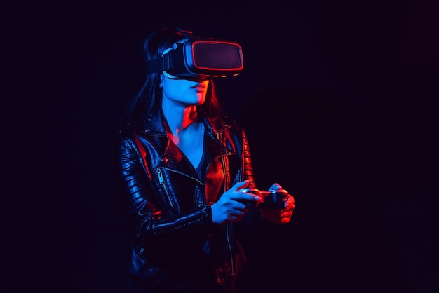 Mädchen mit Virtual-Reality-Brille mit roten und blauen Lichtern auf schwarzem Hintergrund