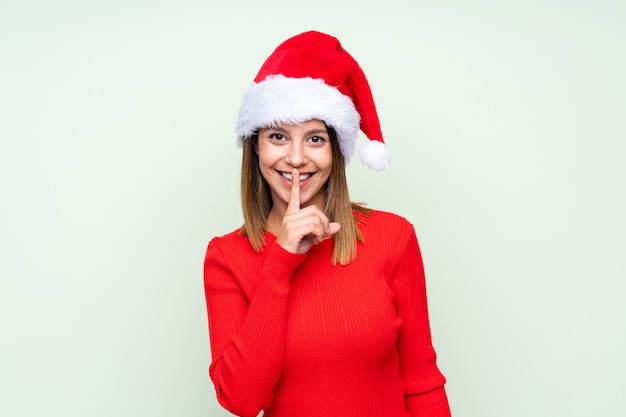 Mädchen mit Weihnachtshut über dem lokalisierten Grün, das Ruhegeste tut