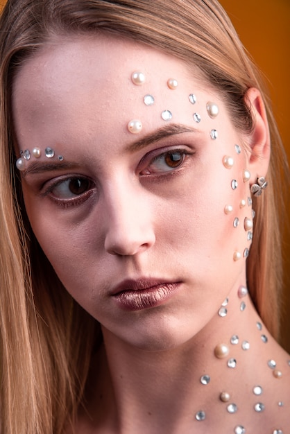 Mädchen mit Weiß- und Perlenrhinestones auf ihrem Gesicht.