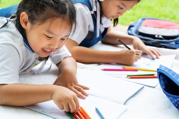 Mädchen mit zwei Schwestern schreibt Buchentscheidung des Lessonemädchens legen Sie das Zeichnen des Bildes nieder