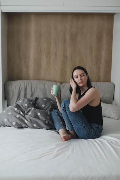 Mädchen morgens im Bett mit einer Tasse Kaffee