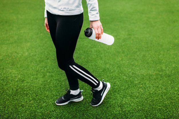 Mädchen nach dem Training, Laufen oder Sport eine Pause. Im Vordergrund eine Flasche Wasser. Das Mädchen arbeitet an der frischen Luft.