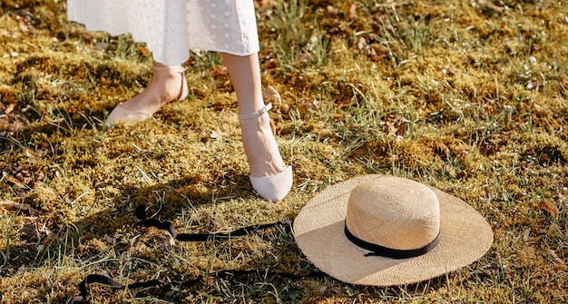 Mädchen nahe einem Strohhut im Garten auf dem Gras. Picknick im Sommer oder Frühling.