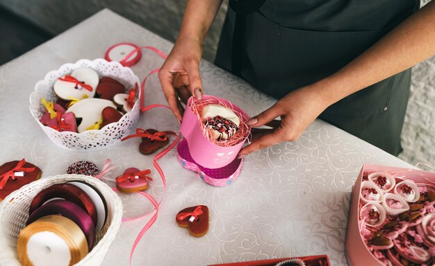 Mädchen packt in einer Geschenkbox Kuchen in Form eines Herzens.